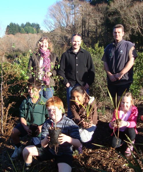 Bayfair Shopping Centre Marketing Manager Nina Rivett, Bayfair Shopping Centre Manager Andrew Wadsworth, and Tauranga City Council Parks Ranger help kids from Maungatapu Primary School and Bellevue Montessori School plant their trees.